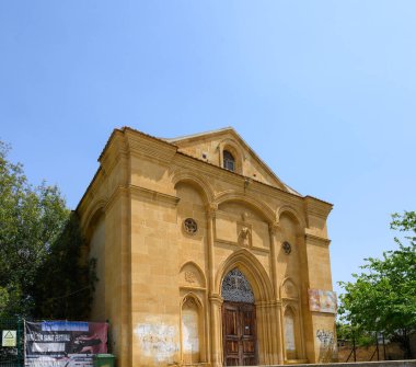 Süslü detayları olan tarihi bir binanın çarpıcı manzarası canlı mavi gökyüzüne doğru yükseliyor. Yeşillik, yapıyı çevreleyerek, olay yerine sükunet ve cazibe katıyor..