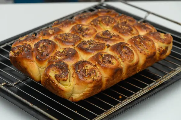 Fırından güzel fırınlanmış bir somun çıkıyor, yumuşak, altın sarısı kahverengi rulo, üzerinde çıtır çıtır kokulu baharatlar sergileniyor. Sıcak mutfak hoş kokularla dolu, herkesi eğlenmeye davet ediyor..