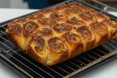 Fırından tatlı baharatlı tarçın ruloları çıkıyor, altın bir kabukla övünüyor ve çıtır çıtır fındık serpiştiriyor, sıcak bir mutfak atmosferinde enfes bir aroma yaratıyor..