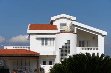 Şık villa, güneşli bir günde verimli yeşilliklerle çevrili çağdaş tasarım elementleri ve temiz çizgiler sergiliyor..