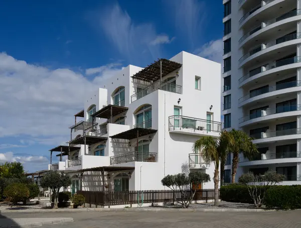 Parlak beyaz binalar canlı bir gökyüzüne karşı zarif bir şekilde duruyor. Çağdaş tarzı ve dingin mimariyi somutlaştırıyor..