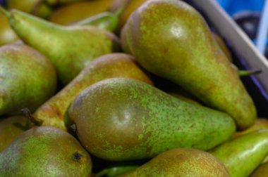 Bereketli yeşil armutlar, canlı bir pazarda taze ürünlerin özünü kutlayarak birlikte zarifçe dinleniyorlar..