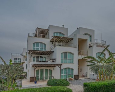 Şık bina, çağdaş mimariyi yemyeşil ile harmanlarken alacakaranlıkta sakin sulara bakıyor.