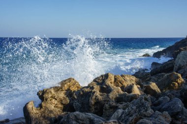 Yumuşak okyanus dalgaları kayalık kıyı şeritleriyle çarpışır ve büyüleyici köpüklü su gösterileri yaratır..