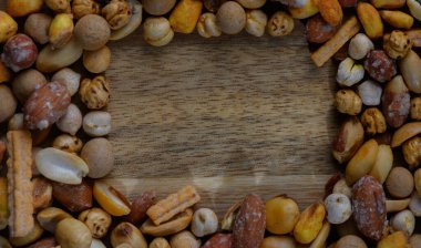 Fındık ve kraker de dahil olmak üzere çeşitli atıştırmalıkların canlı bir koleksiyonu, ahşap bir yüzeyi çerçeveler, kahkaha ve hoş sohbetlerle dolu toplantıları davet eder, her toplanma için mükemmeldir..