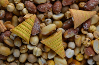 Çeşitli fındıklardan oluşan canlı bir koleksiyon desenli bir temel oluştururken renkli, koni şeklinde atıştırmalıklar eğlenceli bir dokunuş ekliyor. Kutlama ya da arkadaşlarla günlük toplantılar için ideal..