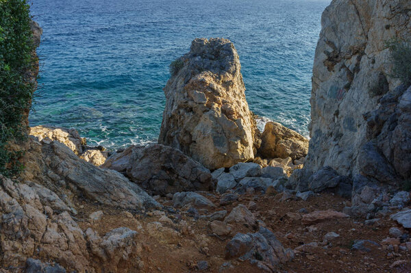 Мягкие волны встречают прочные скалы с восходом солнца, создавая спокойную прибрежную атмосферу.