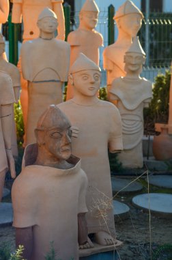 Olağanüstü terracotta heykelleri bir açık hava sergisinde duruyor, akşam güneşinin sıcacık parıltısında güneşleniyorlar..