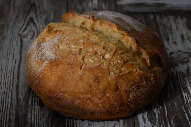 Altın kabuklu esnaf ekmeği, ahşap bir yüzeyde davetkar bir şekilde oturur, fırından taze taze taze çıkartılmaya hazırdır..