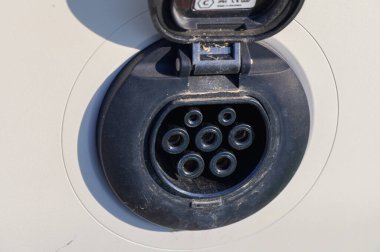 Elektrikli bir araca bağlı EV şarj istasyonu. Sürdürülebilir bir şehir ortamında temiz enerji ve modern ulaşım kavramı.