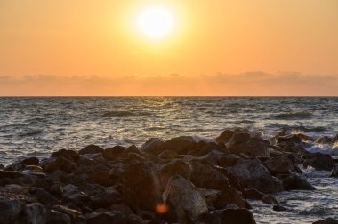 Kıbrıs kıyılarındaki Akdeniz 'in üzerinde altın gün batımı. Canlı gökyüzü renkleri ve sakin dalgalar huzurlu ve romantik bir akşam atmosferi yaratır..