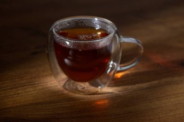 Taze demlenmiş bitki çayının zengin aroması cam bardakta dans eden ışık gibi havayı doldurur..