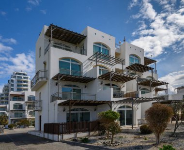 Serene sahil binası çarpıcı bir mimariye sahip, modernliği berrak mavi gökyüzü altında doğal güzellikle harmanlayan.