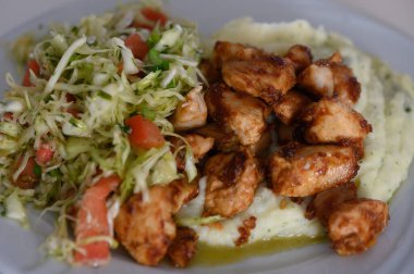 Yumuşak ızgara tavuk parçaları lezzetli baharatlarla parıldıyor, ipeksi patates püresi ve canlı lahana ve domates salatasıyla çiftleştirilmiş, keyifli bir öğle yemeği deneyimi yakalıyor..