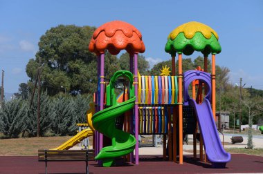 Çocuklar bu canlı oyun parkında kaydırak ve tünelleri olan yüksek bir yapı bulurlardı. Öğleden sonra güneşi neşe saçan gölgeler oluşturur, açık hava eğlencesi için neşeli bir atmosfer yaratır..