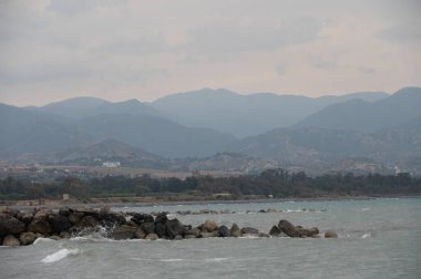 Kıbrıs 'ta dağlı ve plajlı alacakaranlık deniz manzarası