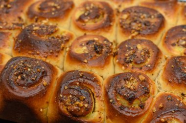 Sıcak, aromatik tarçın ruloları fırından çıkar, altın kabukları tatlı bir jöleyle parlar ve üzerine fındık serpiştirilir. Nefis bir sabah ziyafeti bekliyor.