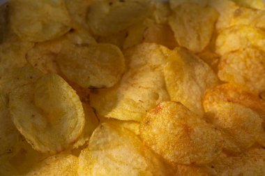 Altın patates cipsi hafif bir ışığın altında parıldar. Sıradan bir toplanma ya da film gecesinde eğlenmeye hazırdırlar..