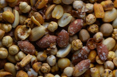 Sergilenen çeşitli kavrulmuş fındık ve tohumlar, renklerin ve dokuların enfes bir karışımını sergiliyor. Mükemmel kavrulmuş, sıradan bir sosyal ortamda tatmaya davet ediyorlar, çıtırtılarıyla herkesi baştan çıkarıyorlar..