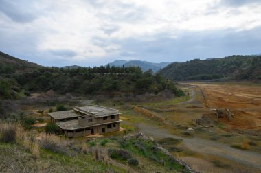 Issız bir bina, kayan tepeler ve bulutlu gökyüzü ile çevrili, ıssız bir arazide duruyor. Ürkütücü bir terk edilmişlik hissi uyandırıyor ve solmuş anılar..