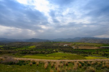 Girdap gibi dönen bulutların altında, yemyeşil tepeler ufuk boyunca uzanıyor, sakin bir kırsal alanda keşifleri davet ediyor. Doğa bu huzurlu manzarada gelişir..