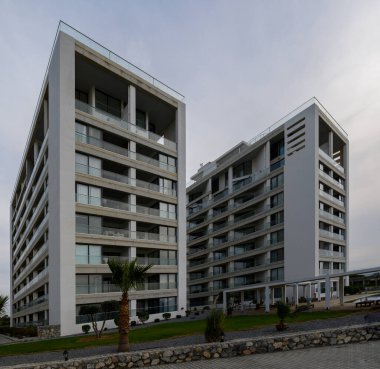 Şık binalar kasvetli bir gökyüzüne karşı yükseliyor, modern mimari unsurları ve sakin çevreyi sergiliyor..