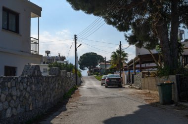 Taştan duvarlar, evler ve yukarıdaki açık mavi gökyüzü ile çevrili bir sahil köyünde tuhaf bir ara sokak..