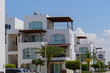 Kıbrıs 'taki modern beyaz villalar parlak Akdeniz güneşinin altında. Mavi gökyüzü, palmiye ağaçları ve zarif mimari mükemmel bir tatil ve gayrimenkul ortamı yaratır..