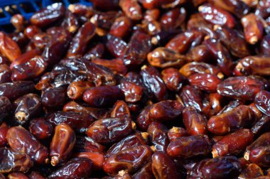 Canlı bir pazarda taze toplanmış kuru hurma güneş ışığında ışıldar zengin renkler ve dokular sergilenir..