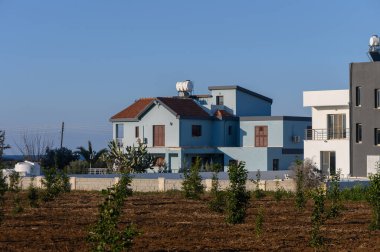 Yeşil tarlalar ve sükunetle kucaklanmış, berrak gökyüzünün arka planına gururla bakan büyüleyici mavi bir ev..
