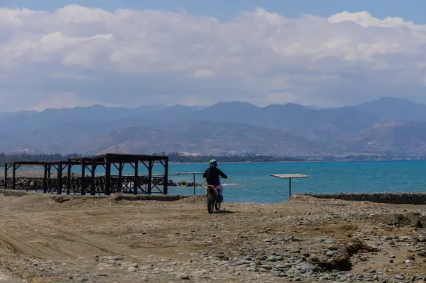 Kıbrıs Rum Kesimi 'nin Akdeniz kıyısındaki kumlu plajı boyunca motosikletli. Güzel deniz manzarası, özgürlük hissi, seyahat, yaşam tarzı ve motor sporu içeriği için mükemmel..