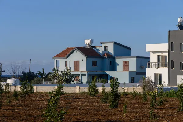 Yeşil tarlalar ve sükunetle kucaklanmış, berrak gökyüzünün arka planına gururla bakan büyüleyici mavi bir ev..