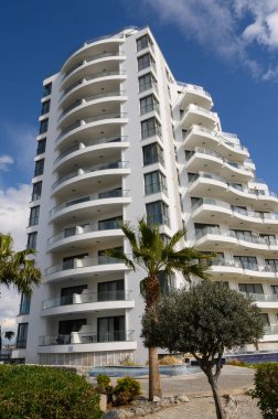 Sersemletici çok katlı bina, bereketli yeşilliklerle çevrili canlı bir gökyüzüne karşı gururla duruyor ve kıyıdan huzurlu bir kaçış öneriyor. Modern mimari ve doğanın mükemmel bir karışımı..