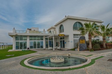 Kıyı şeridinin yanındaki lüks villa modern mimariyi ve güzel bir çeşmeyle huzurlu çevreyi sergiliyor..