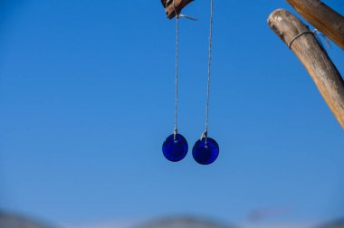 Parlak gök kubbenin altındaki ahşap bir yapıdan sarkan iki parlak mavi cam küre kıyı atmosferinin dinginliğini yansıtan çarpıcı bir kontrastlık oluşturuyor..