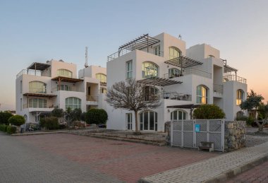 Alacakaranlık sıcacık bir parıltı saçarken yemyeşil balkonlarla bezenmiş büyüleyici beyaz binalar ortaya çıkıyor..