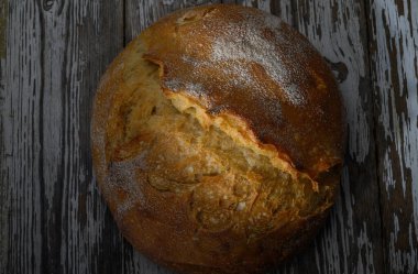 Dışı çıtır çıtır olan altın kahverengimsi ekmek, yıpranmış ahşabın üzerinde oturur ve ev yapımı yemekleri davet eder..