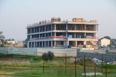 İşçiler, alacakaranlıkta sakin bir zemin karşısında ilerleme kaydetmek için, çok katlı bir yapı üzerinde özenle işbirliği yapıyorlar..