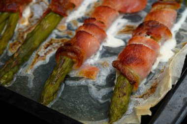 Kuşkonmaz sapları gevrek pancetta ile kaplıdır. Fırın tepsisinde altın kahverengiye dönmüştür. Bu cezbedici yemek pişirirken Aromalar sıcacık bir mutfakta havayı dolduruyor..