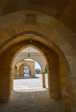 Taş kemerler, sakin bir avluya çıkan güzel bir geçit yaratır. Parlak güneş ışığı karmaşık mimariyi aydınlatır. Gezginleri tarihini keşfetmeye davet eder..