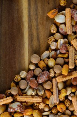 Ahşap bir kaseden çıkan çeşitli çıtır çıtır atıştırmalıklar, canlı renklerle dolu, enfes bir karışım sergiliyor..