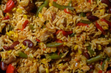 Lezzetli bir pirinç, fasulye ve renkli sebze karışımı sıcak bir yemeği doldurur ve herkesi doyurucu bir yemeğe davet eder..