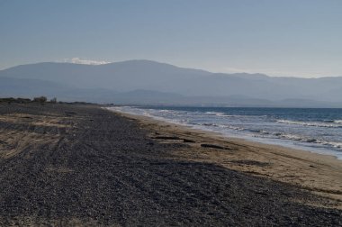 Sakin bir sahil boyunca uzanan altın kumlar yumuşak dalgaların sisli bir alacakaranlık gökyüzünün altında kumsalı okşaması gibi..