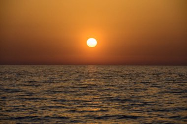 Güneş yavaşça Akdeniz 'e batıyor. Kıbrıs kıyıları açıklarında. Suya doğru altın bir yol açıyor..