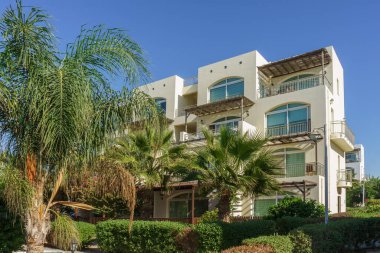 Palmiyeler kıyı şeridinin zarif balkonlarının yanında sallanıyor. Parlak öğleden sonra güneşinin tadını çıkarıyorlar..