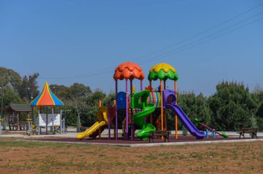 Canlı oyun alanı ekipmanları, kıvrımlı slaytlar ve tuhaf tasarımlar içeren, çocuklar için eğlenceli bir alan sunuyor. Bereketli yeşilliklerle çevrili aileler güneşli havanın tadını çıkarıyorlar..