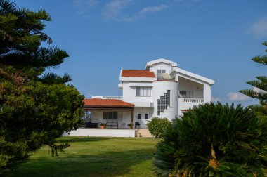 Büyüleyici villa canlı yeşilliklerin arasında gururla duruyor, güneşli bir günde huzurlu bir atmosfer sergiliyor..