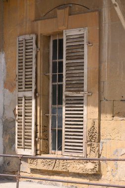 Güneş ışığı, ihmal edilmiş bir binanın eski ahşap kepenklerinden süzülüp solmuş taş duvarlara yumuşak gölgeler bırakıyor. Zaman bu tarihi yapıya işaretini kazıdı, geçmişin hikayelerini fısıldadı..