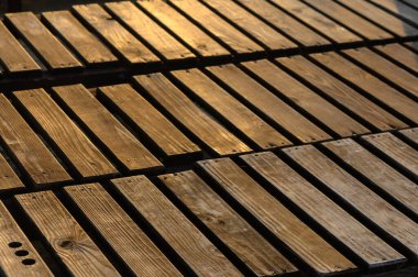 Güneş ışığı, özenle düzenlenmiş ahşap desenleri aydınlatır. Özgün dokularını ve tahıllarını sergiler..