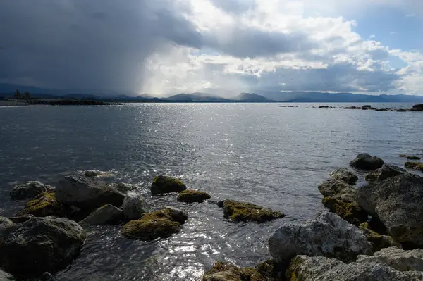 Dalgalar yavaşça kaya çıkıntılarına çarpıyor ufukta karanlık bulutlar belirdikçe sakin bir atmosfer yaratıyor. Alacakaranlık saatlerinde yaklaşan fırtınayı işaret ediyorlar..